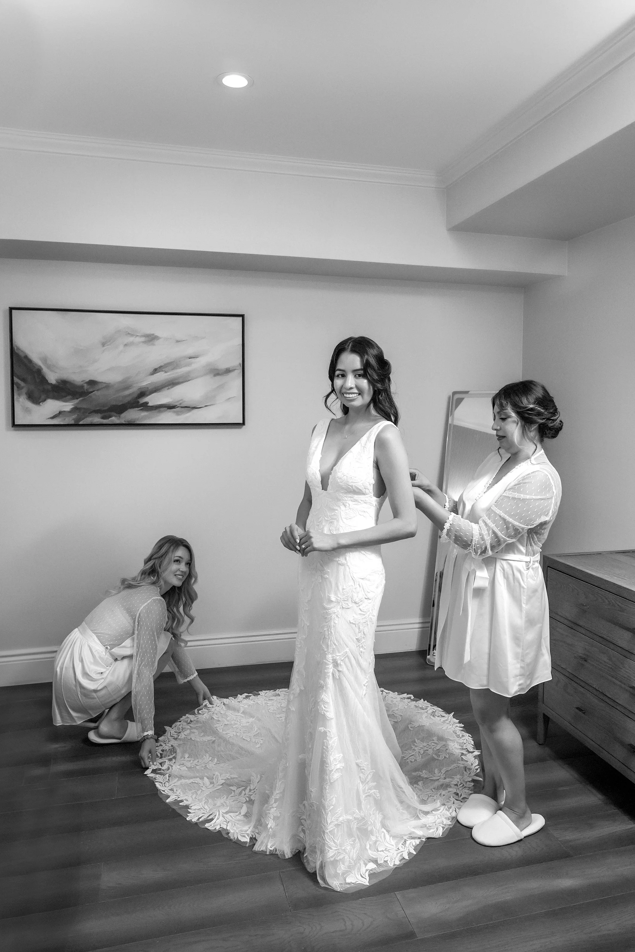 Bride in a lace wedding dress getting ready with bridesmaids at a local boutique hotel before her wedding ceremony.
