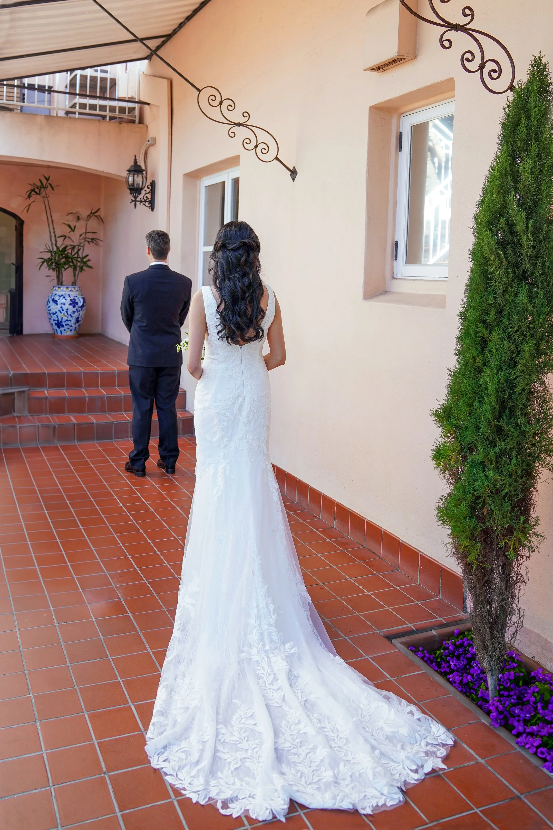 Bride showing the back of her lace train during a first look wedding portrait on the patio at La Valencia Hotel in La Jolla, San Diego.