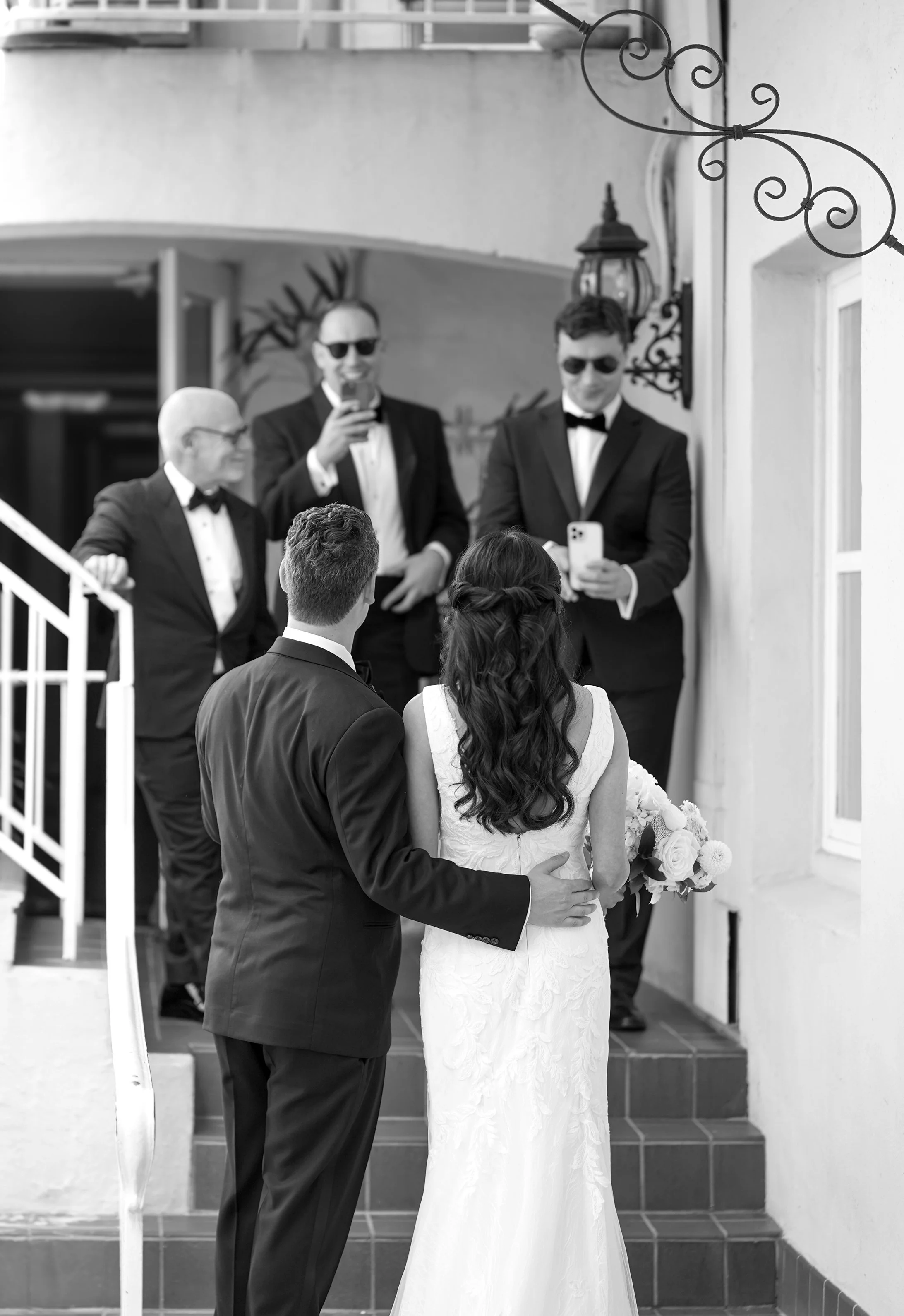 Black and white photo of a bride and groom walking up steps toward wedding guests during their reception entrance at La Valencia Hotel in La Jolla, San Diego.