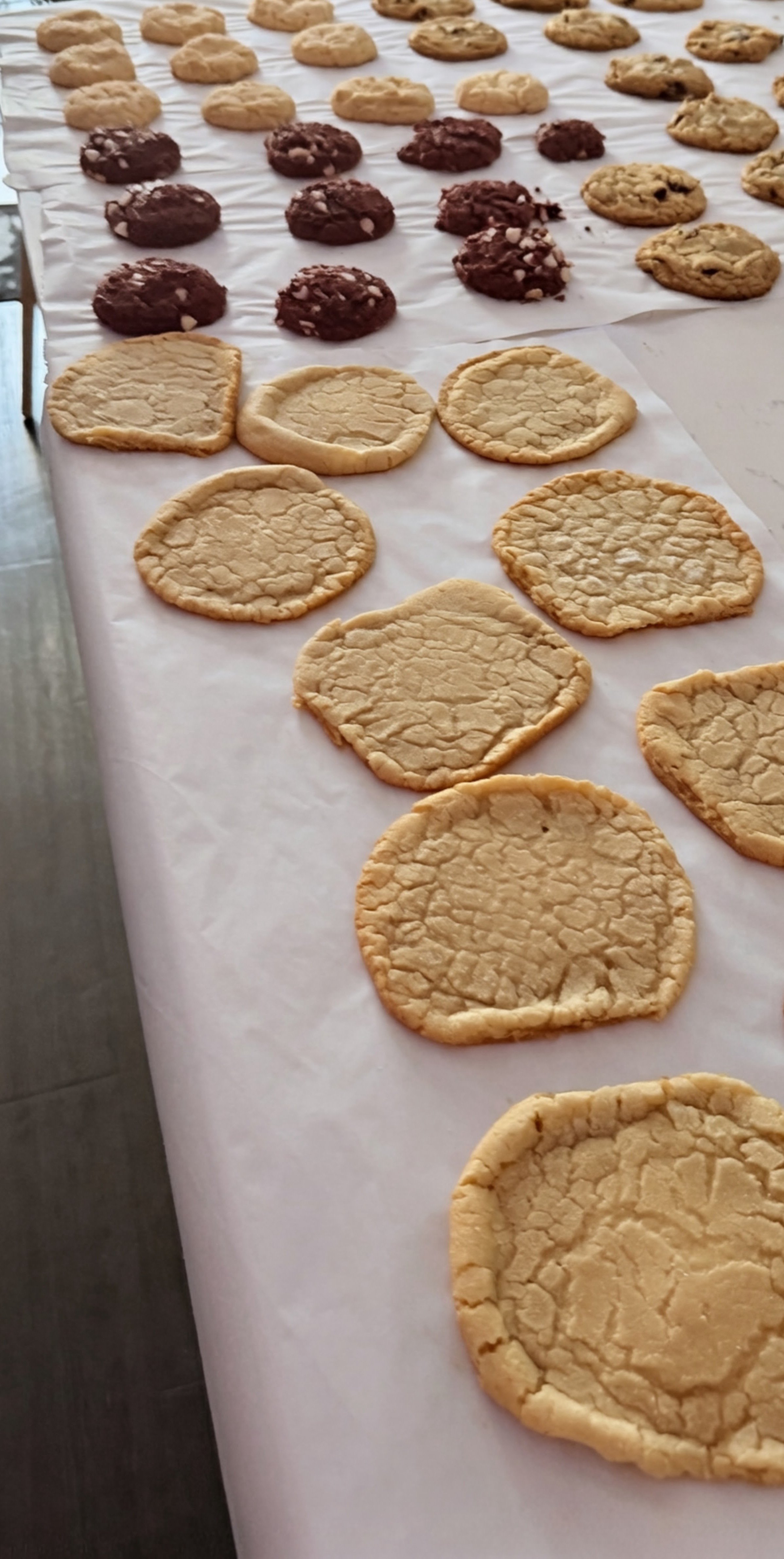 Various cookies in different stages of preparation on a white surface; some are unbaked cookie dough, some are partially baked, and some are fully baked.