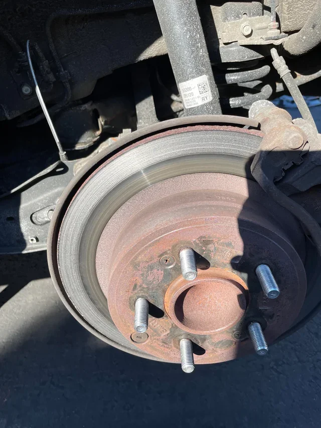 A vehicle with the front wheel removed, showing the brake rotor and hub assembly.
