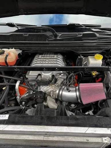 View of a car engine bay with a cold air intake system, an oil fill cap, and other engine components.