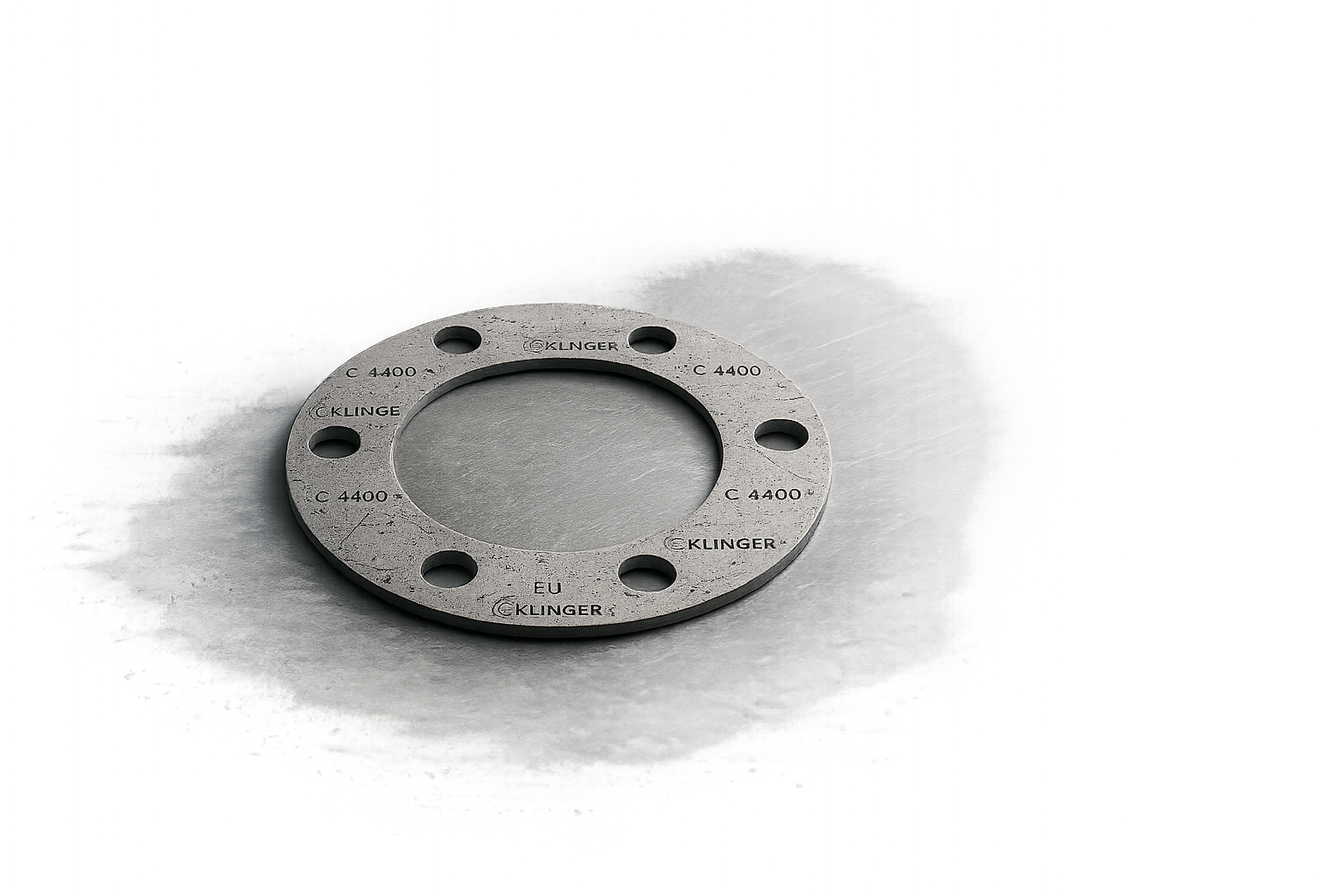 A metallic flange with six holes, inscribed with words 'KLINGER', 'C 4400', and 'EU', resting on a gray surface.