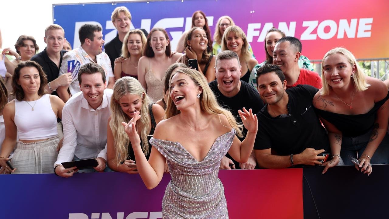 A group of people smiling and enjoying themselves at an event with a backdrop reading "Fan Zone." The woman in the foreground is wearing a sparkly dress and appears to be a celebrity or performer.