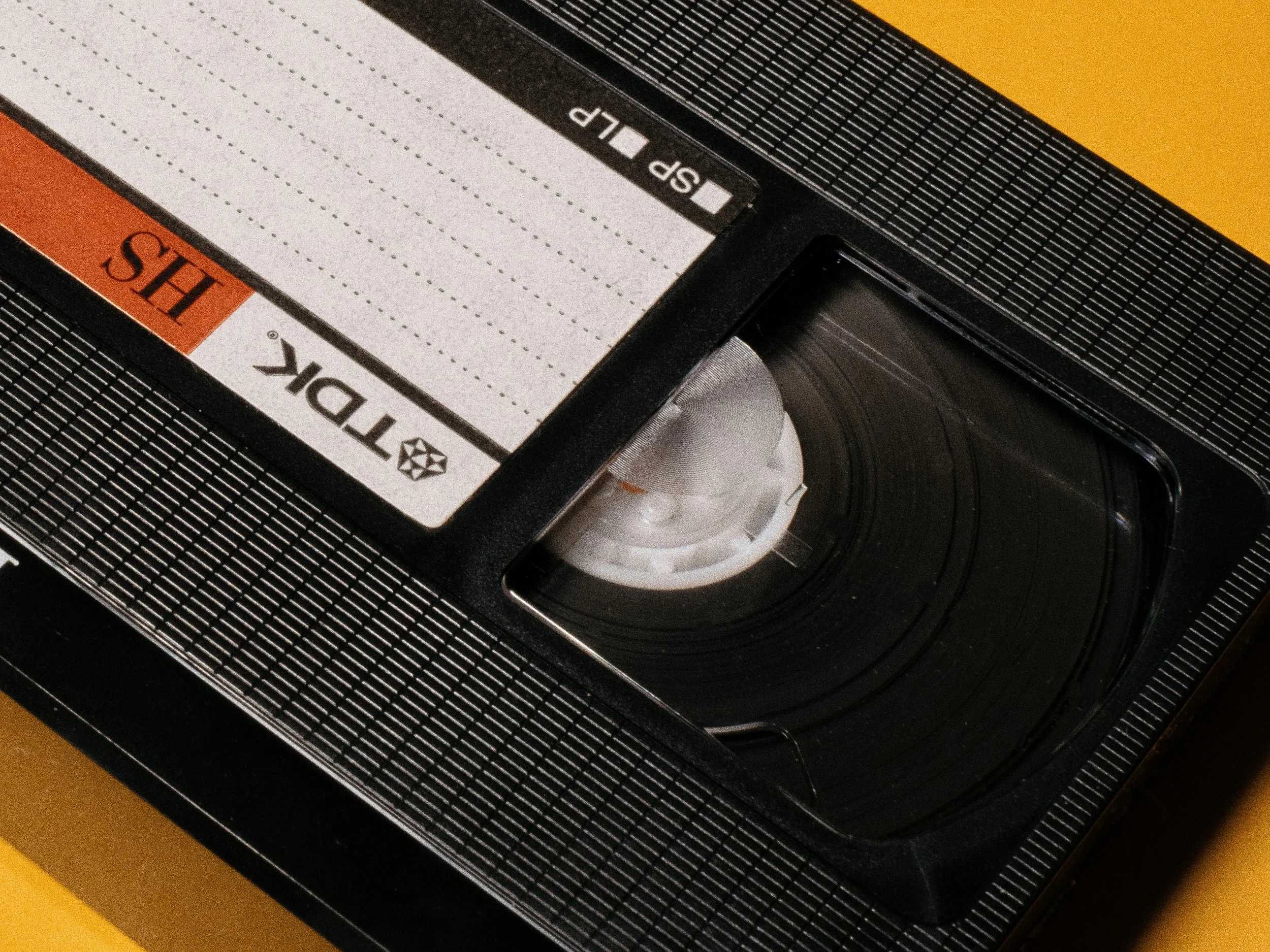 Close-up of a vintage film camera showing the top section with audio and video controls, including a white control knob, and some textured black surface.
