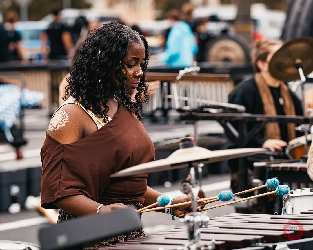 A woman playing a marimba percussion instrument at an outdoor music event.