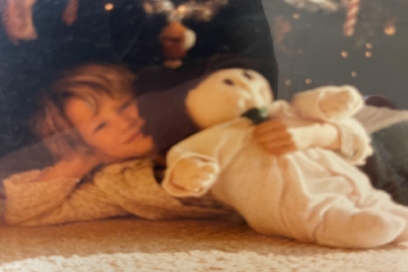 Child lying on a carpet next to a plush stuffed animal