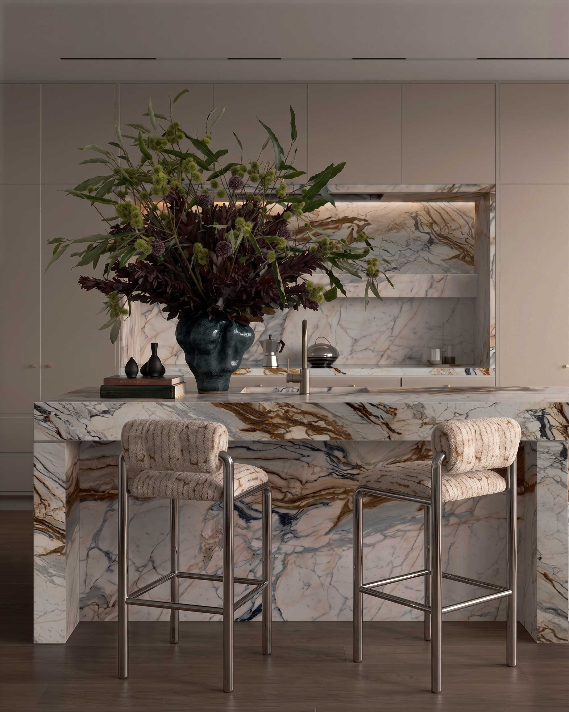 A modern kitchen with a marble island, a dark vase with a large floral arrangement, and upholstered chairs.