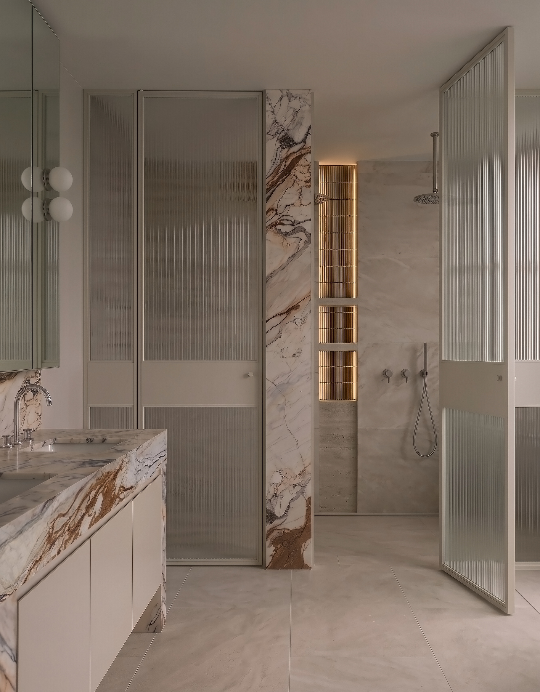 Modern bathroom with marble and glass decor, featuring a marble countertop, marble wall, and separated shower with sliding glass doors and marble walls.
