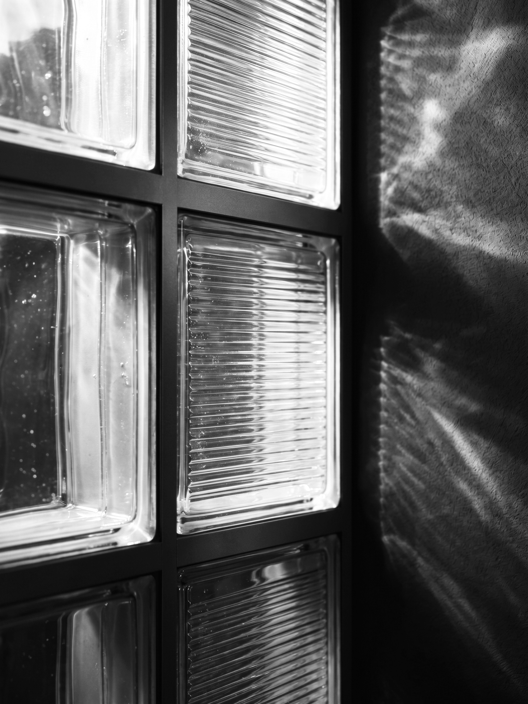 Close-up of a glass block wall with sunlight casting shadows.