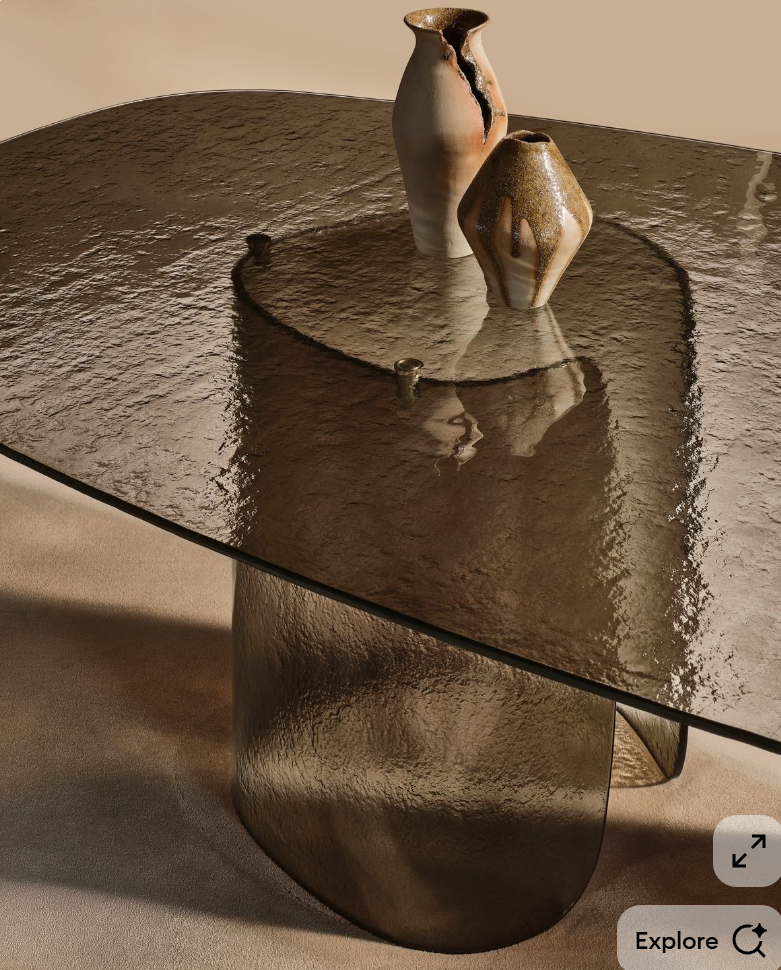 A modern artistic coffee table with a textured, curved metallic base and a reflective glass top, decorated with two abstract ceramic vases.