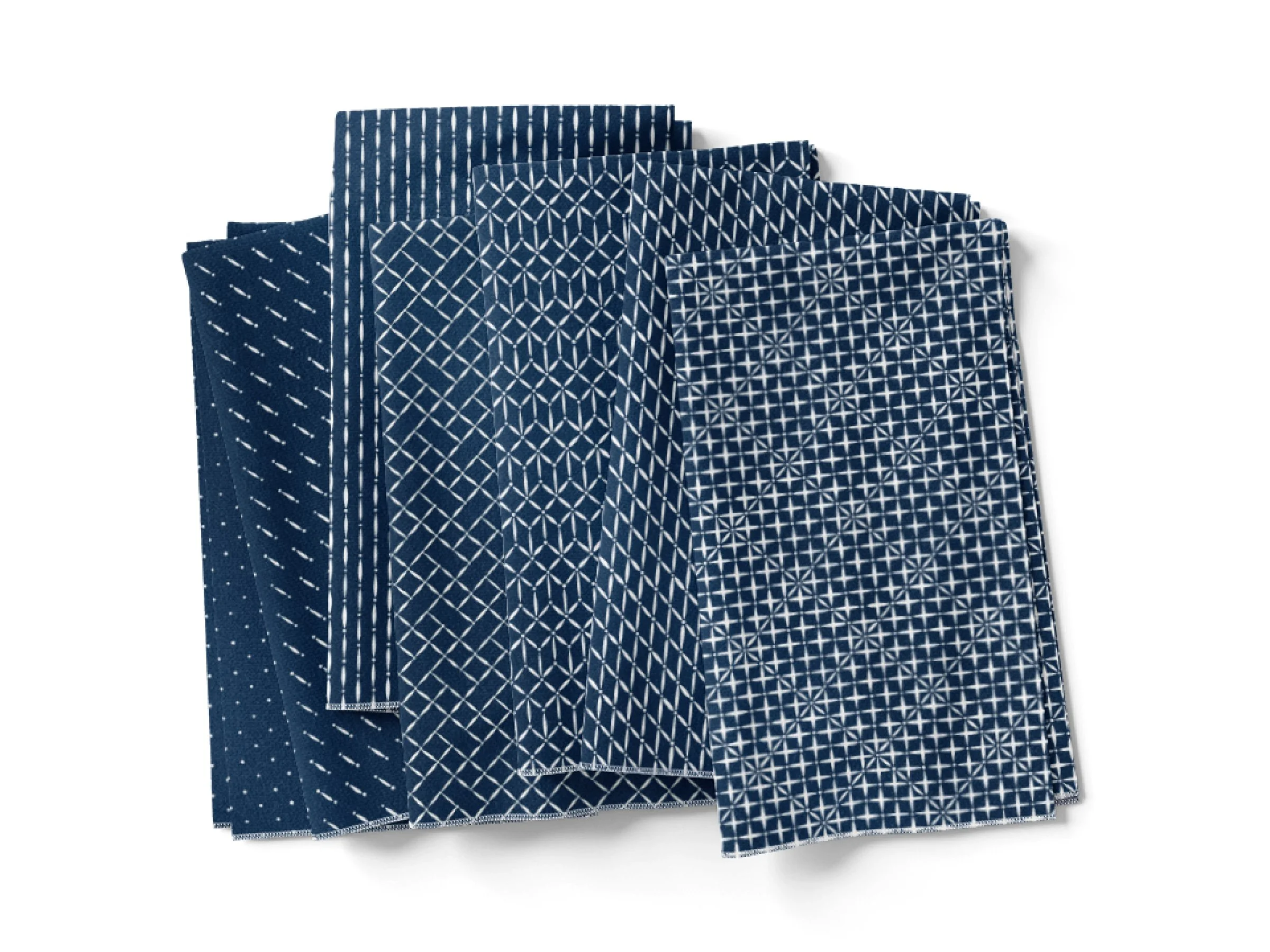 Six folded blue and white cloth napkins with white geometric patterns, arranged on a white surface.