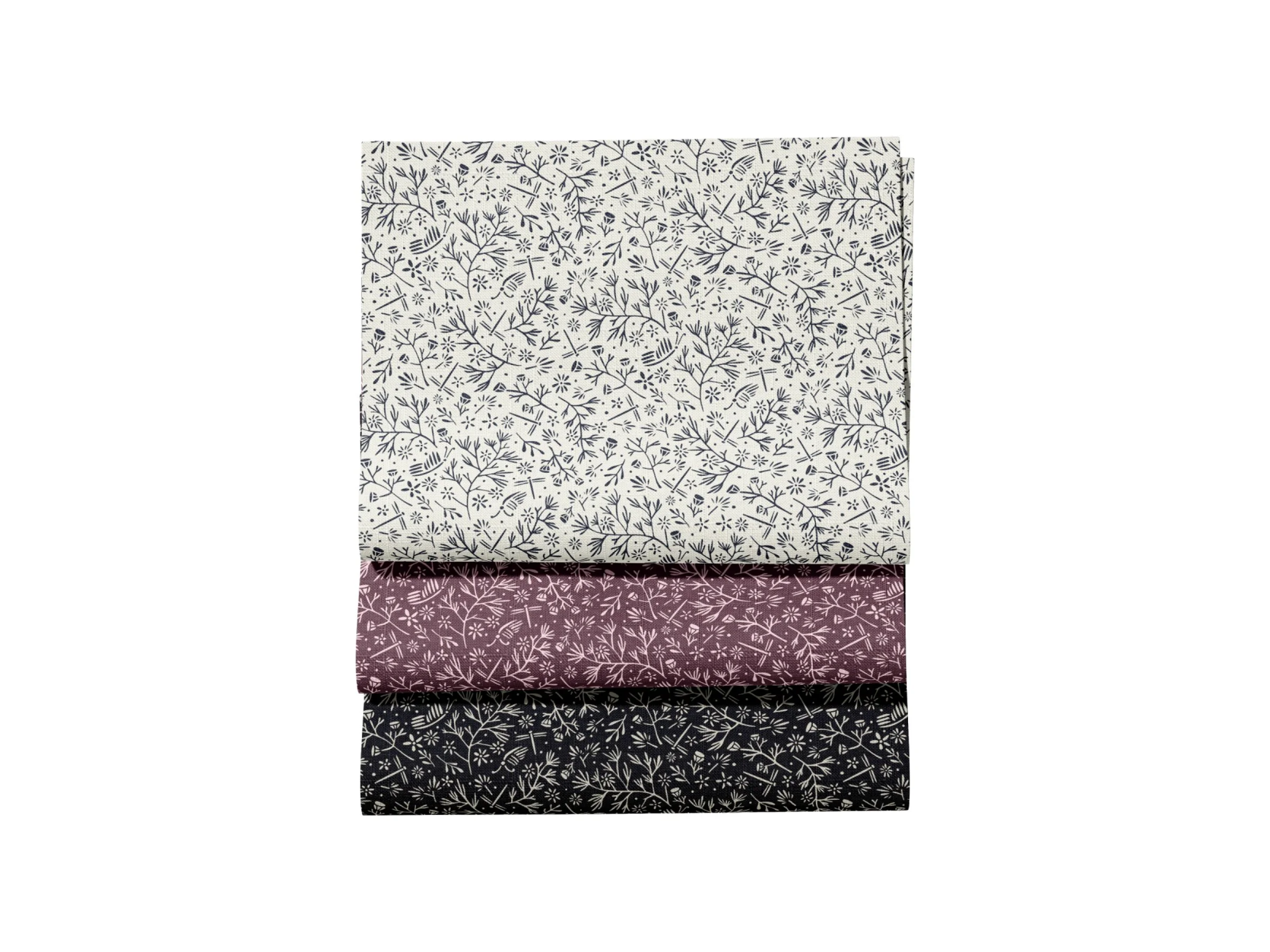 Stacked fabric pieces with various floral and branch patterns in black, white, purple, and dark gray colors.