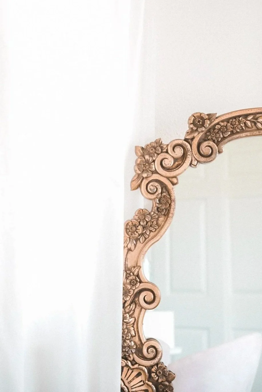 Ornate mirror with floral and scroll details on the frame, partially visible in the image.