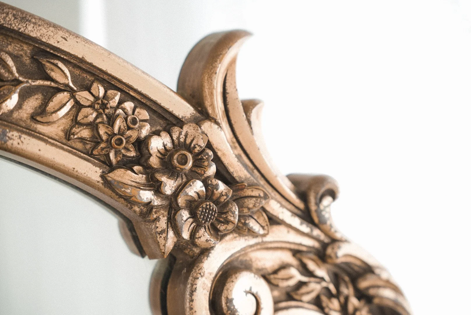 Close-up of an ornate carved wooden decorative piece with floral and scroll patterns, finished in a gold tone.