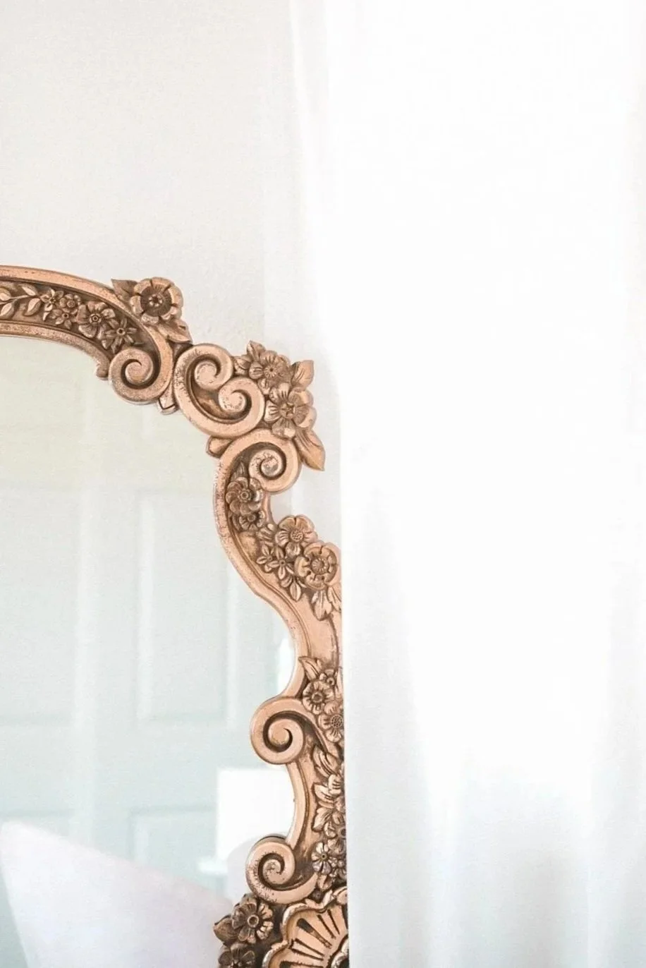 Close-up of an ornate, floral carved wooden frame of a mirror.