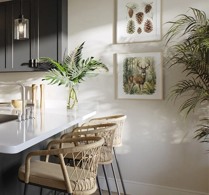 Modern kitchen with white countertop, wicker bar stools, plants, and nature-themed artwork including leaves and a deer at Mill + Miss Apartments in Grand Rapids, MN.