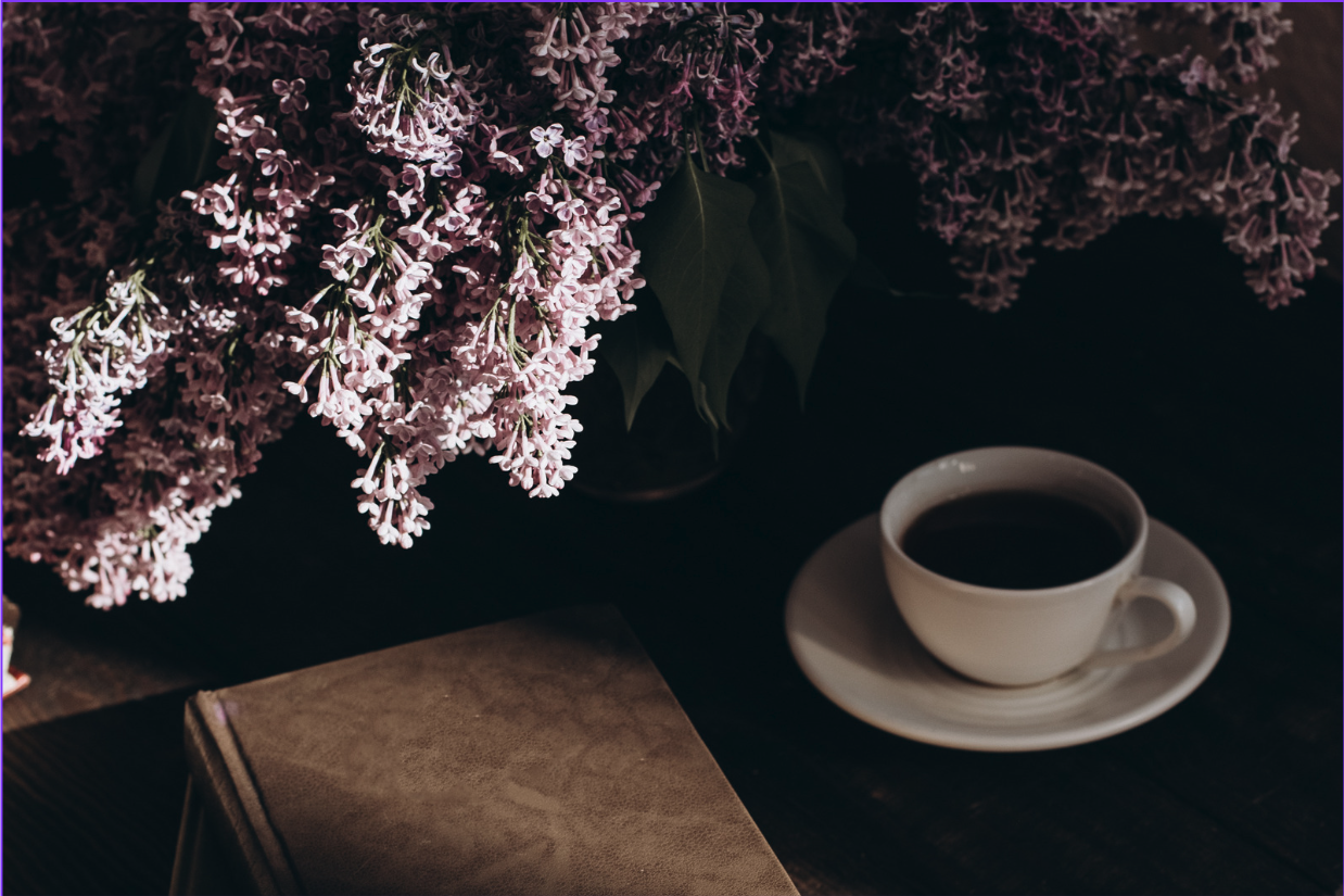 Livre, tasse de café et lilas roses, un rituel de pause et de douceur