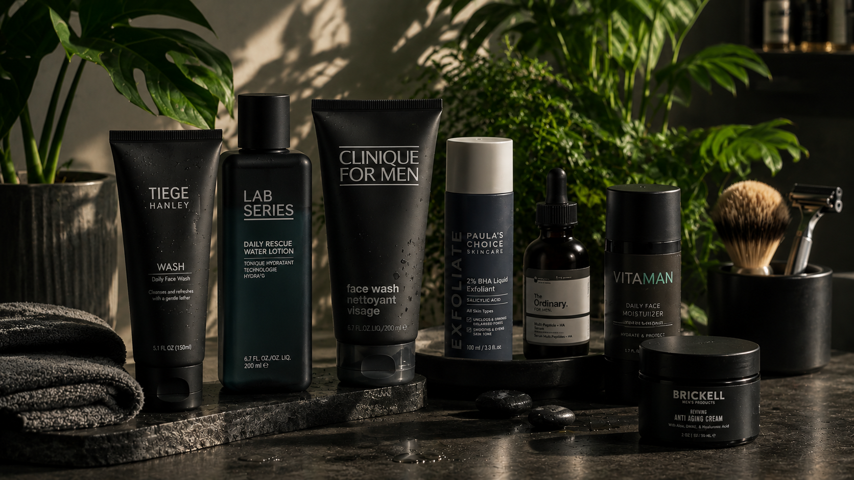 A collection of skincare and grooming products arranged on a dark marble surface with green plants in the background.