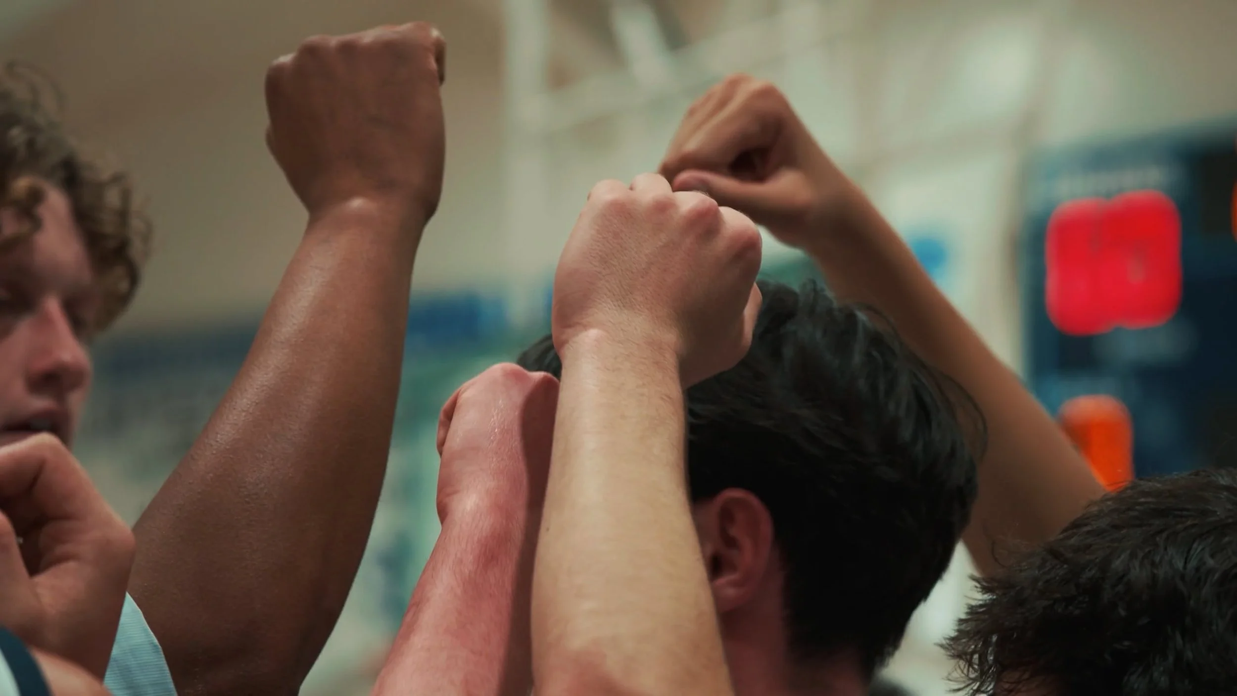 Group of people with their fists raised in a team huddle.