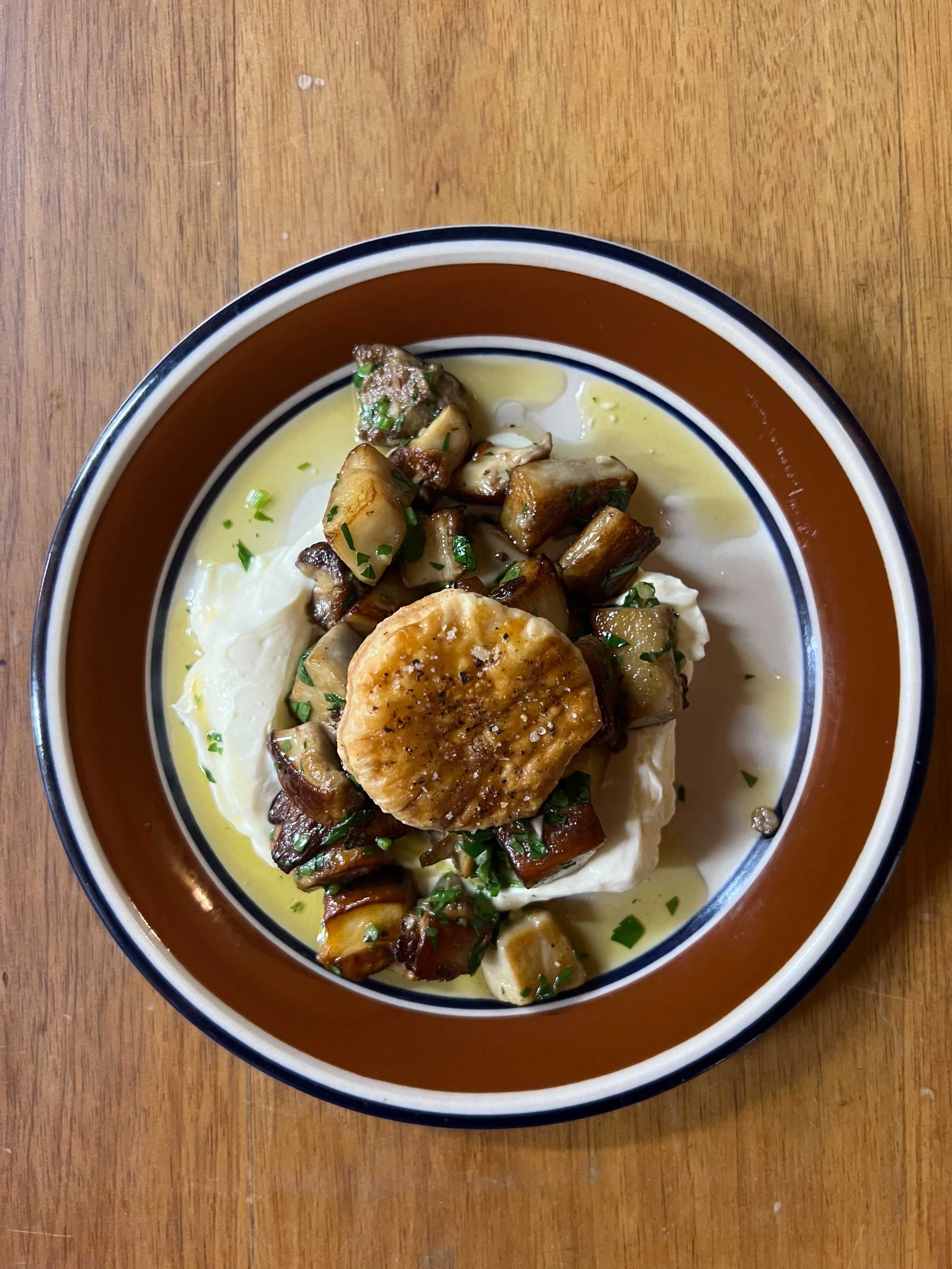 A bowl of food containing roasted vegetables, a poached egg, and creamy mashed potatoes, garnished with chopped herbs.