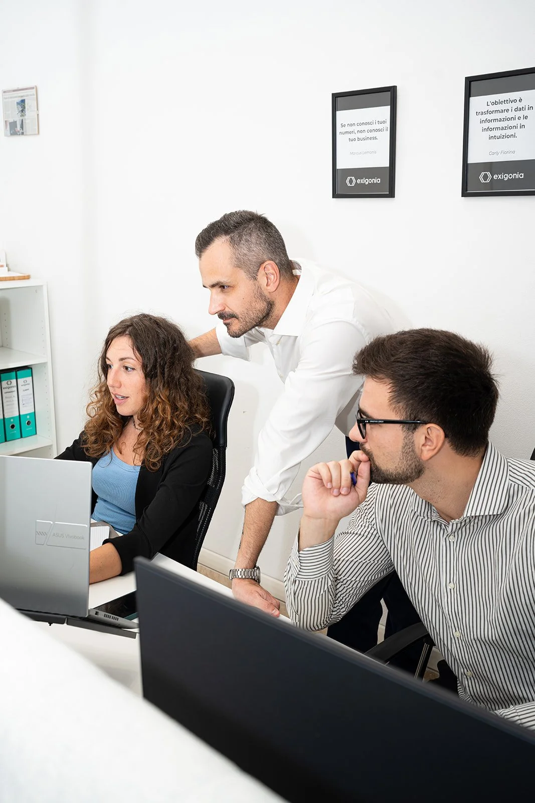Tre persone in un ufficio lavorano insieme davanti a un computer portatile.