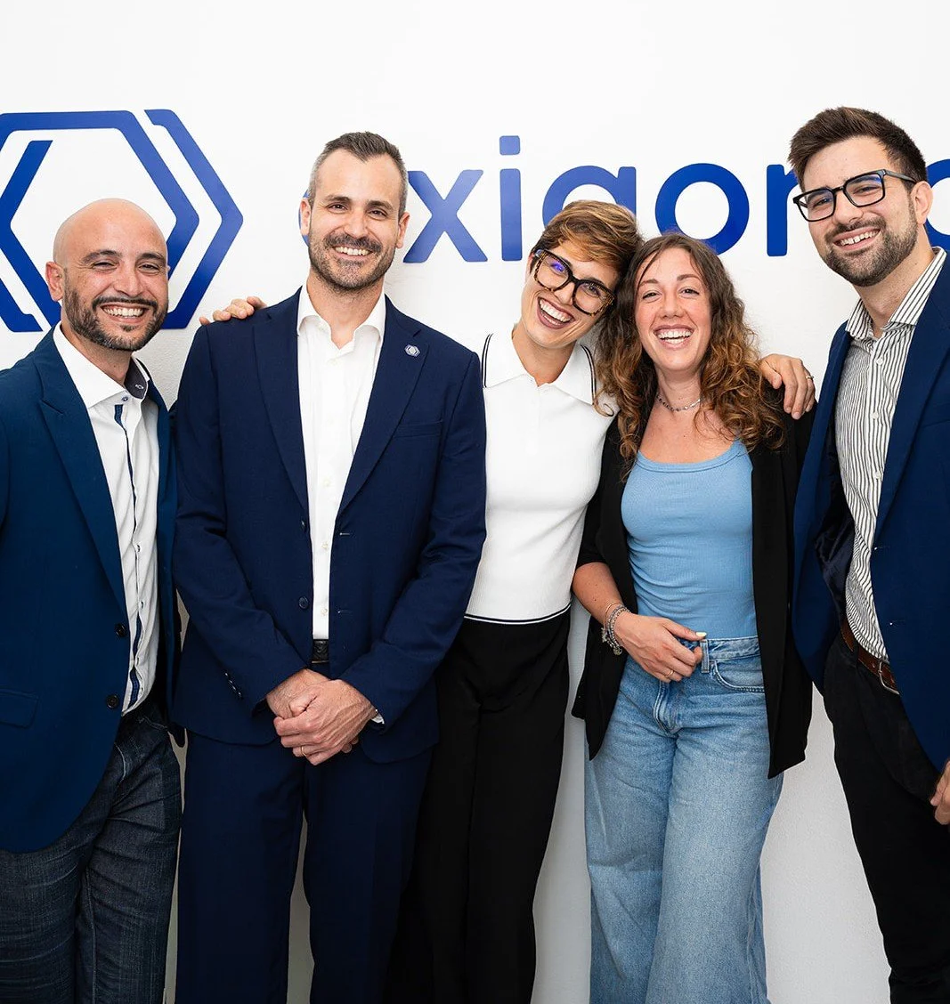Il team Exigonia sorride in una foto di gruppo davanti al logo di exigonia.