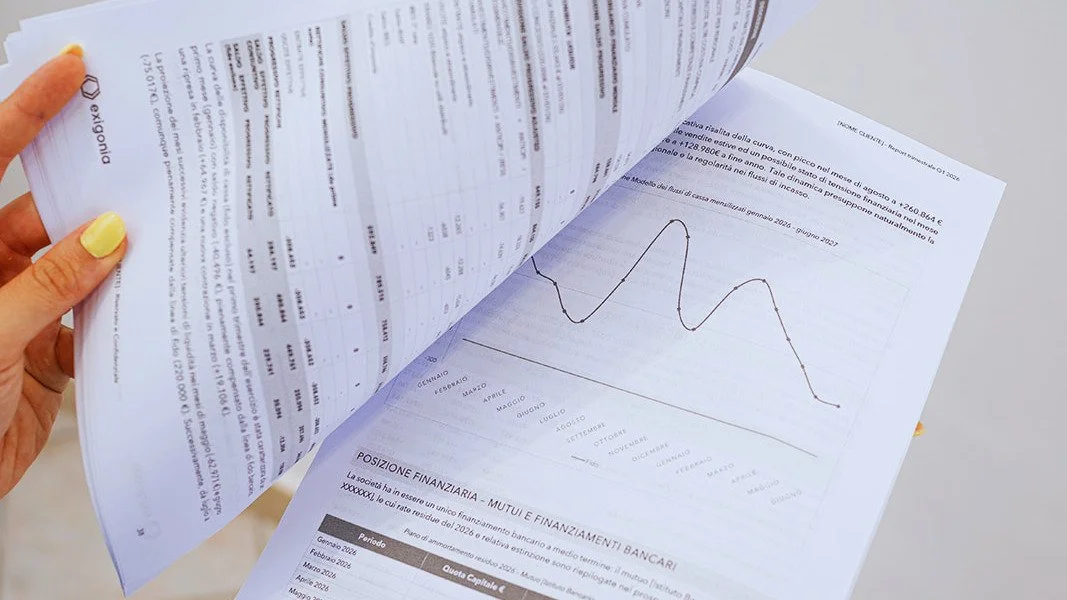 Pagina di un documento finanziario con grafico lineare e dati numerici, tenuto da una mano con unghie gialle