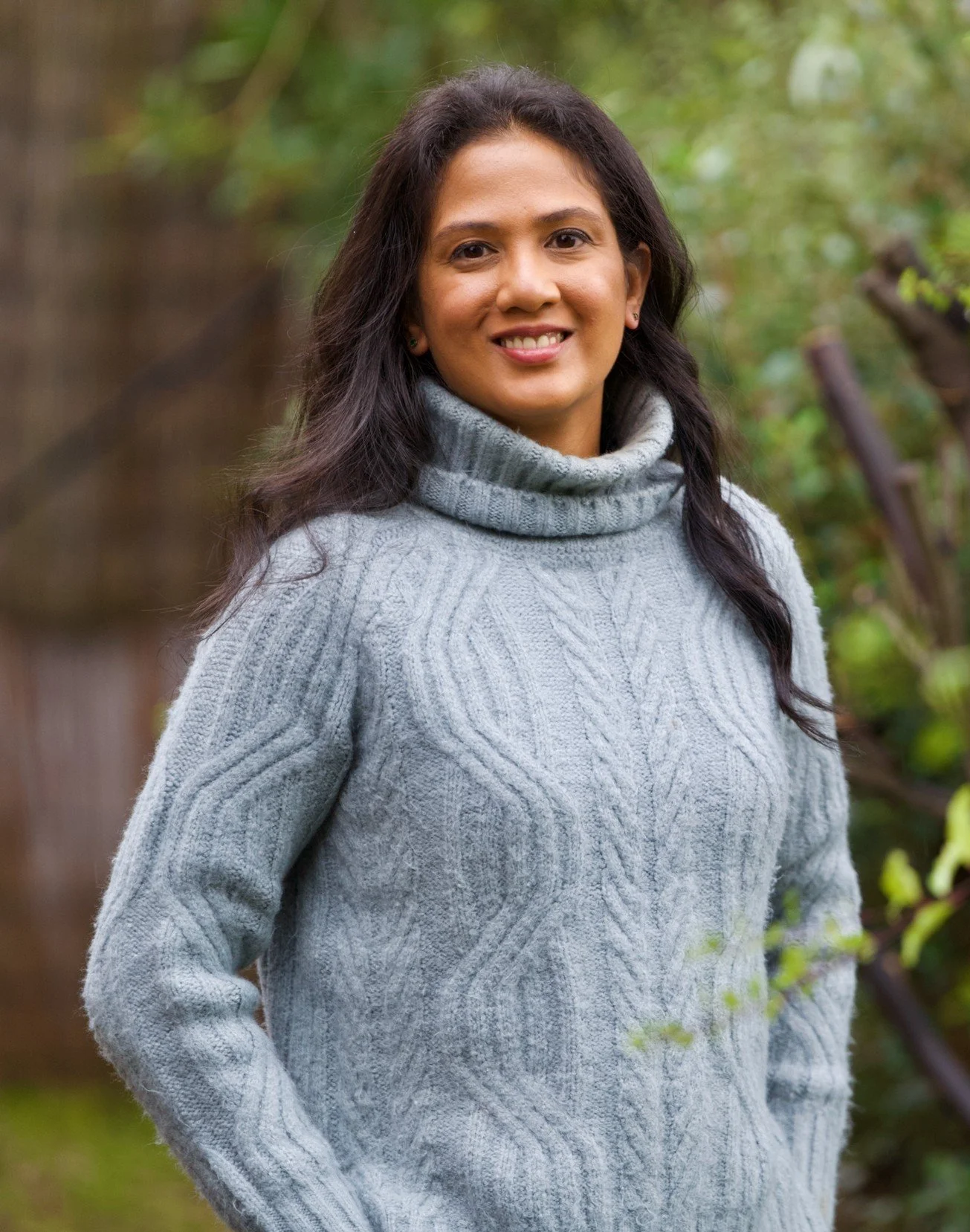 Annabelle Cangy, founder of Get Unstuck Coaching, NLP and Neuro-Semantic coach in Melbourne, standing outdoors with green foliage in the background.