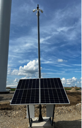 Solar panel installation outdoors with a metal pole and a blue sky with clouds in the background.