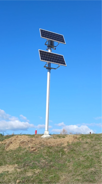 Solar panel installation on a tall pole against a blue sky with clouds.