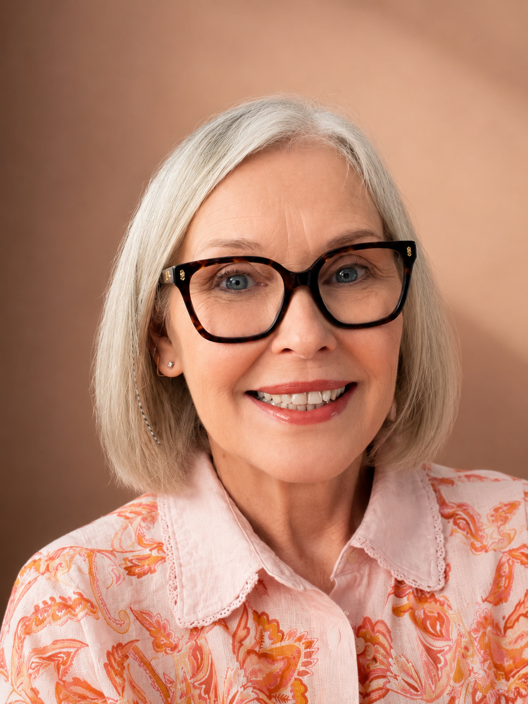Close-up portrait of Jayne Walsh the founder of Paper Foxes Art, wearing large tortoiseshell glasses and a light pink blouse with orange floral patterns.