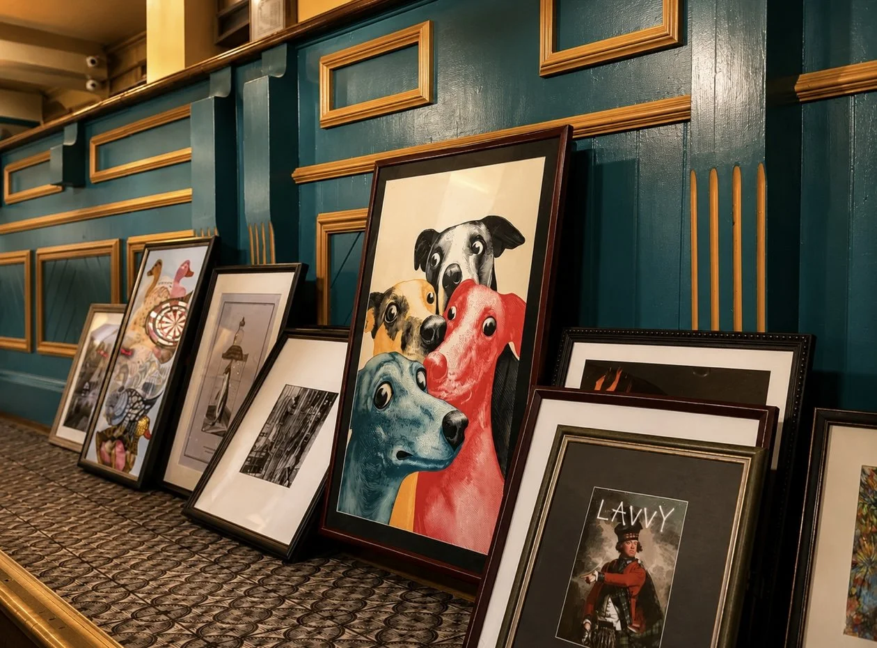 Multiple framed artworks resting against a teal wall with gold accents, featuring various subjects including dogs, abstract patterns, a person in historical attire, and other artwork styles.