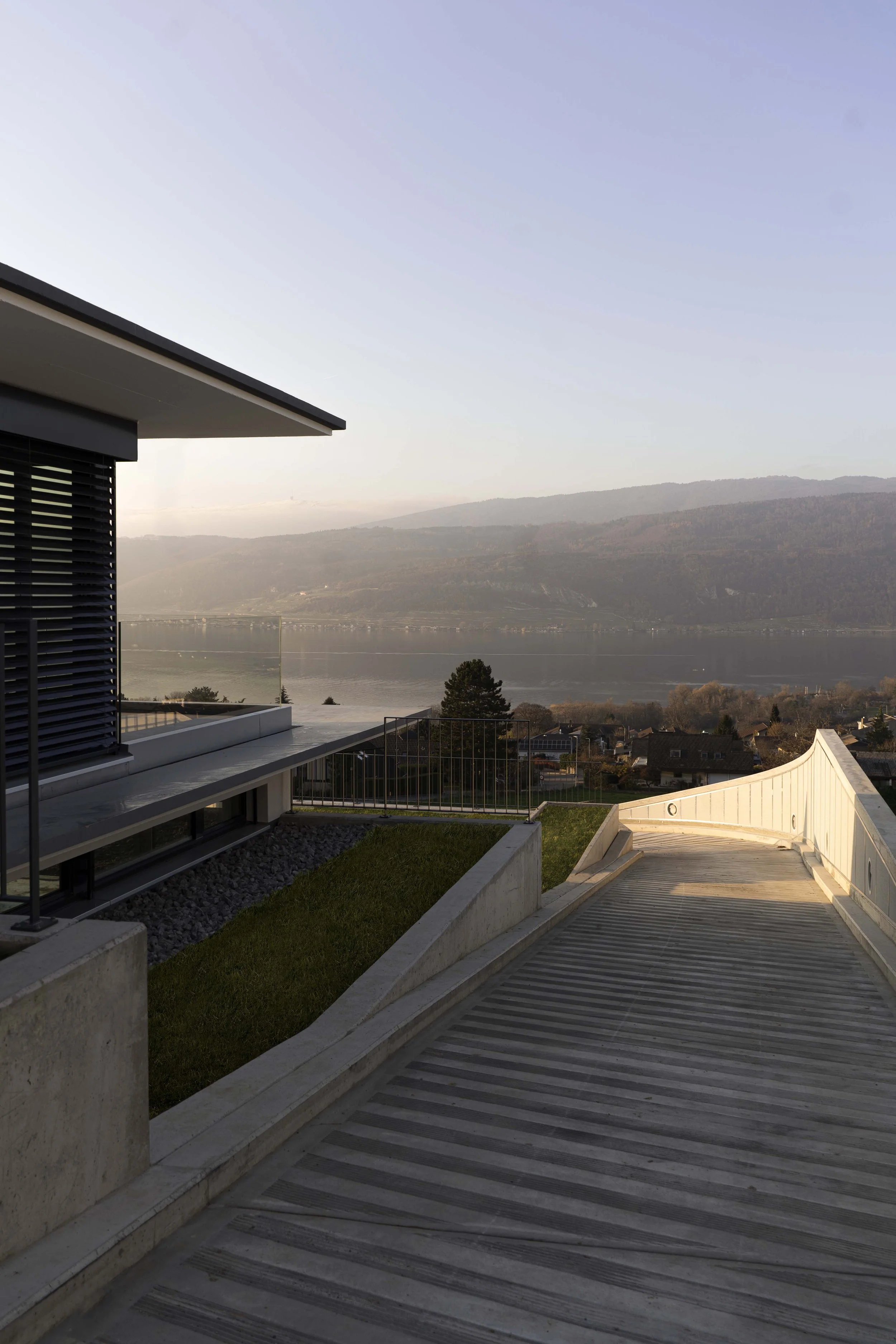 Moderner Balkon mit Blick auf einen Fluss und Berge im Hintergrund bei Sonnenuntergang.