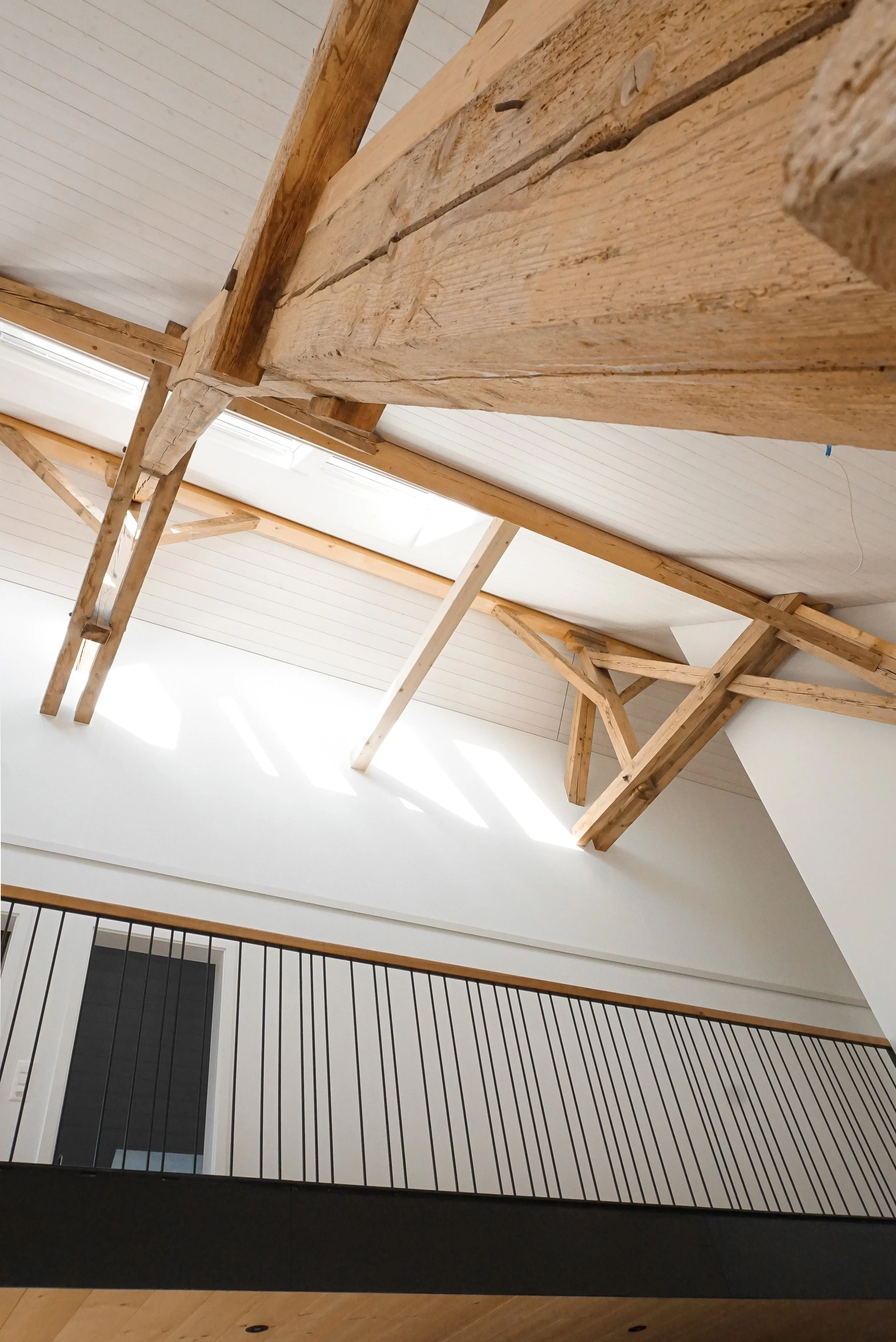 Decke und Balkon im Innenbereich eines Gebäudes, Holzarbeiten, Dachfenster, Balustrade mit schwarzen Stäben.
