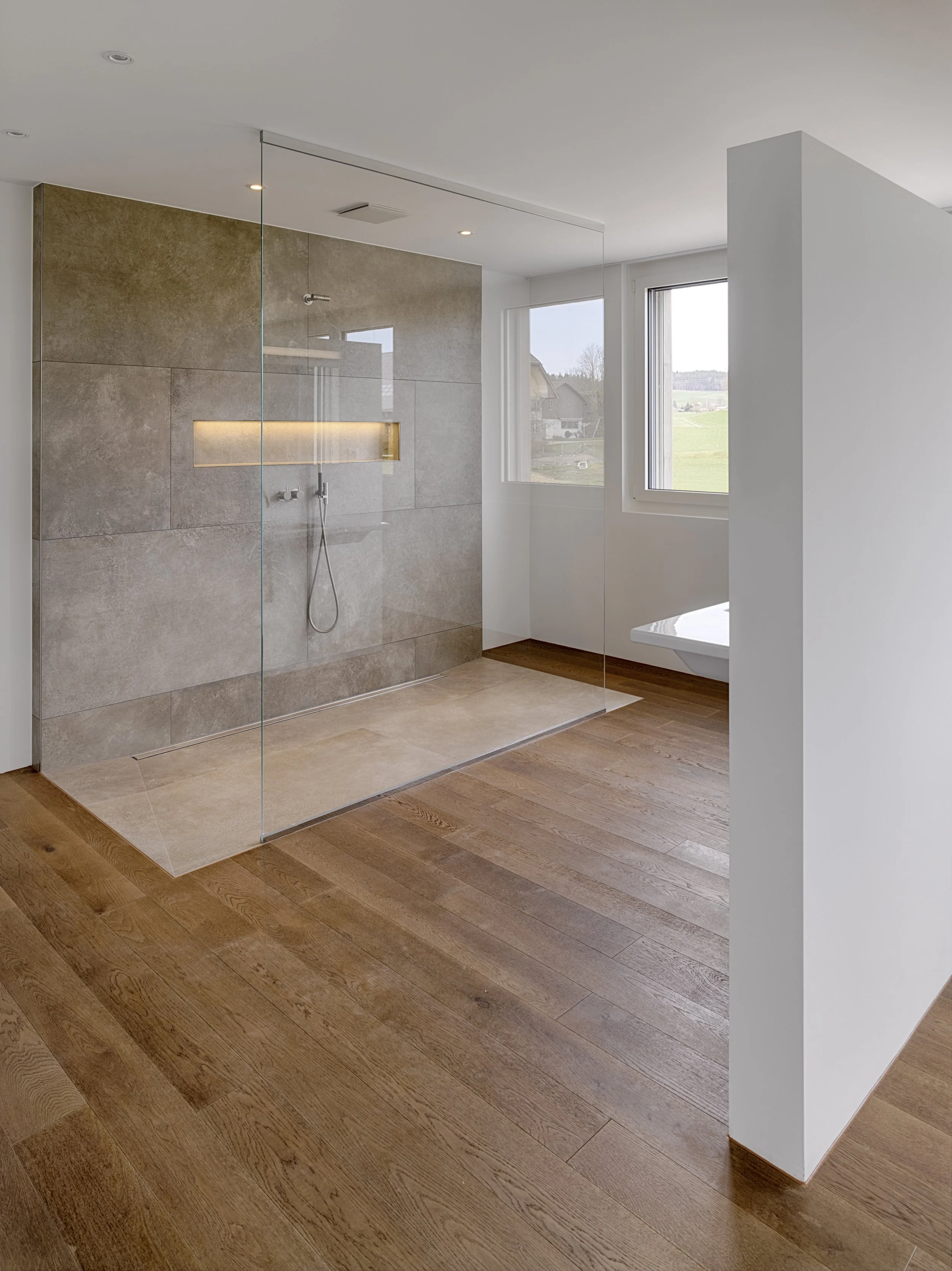 Modernes Badezimmer mit begehbarer Dusche, großen Fenstern und Holzboden.