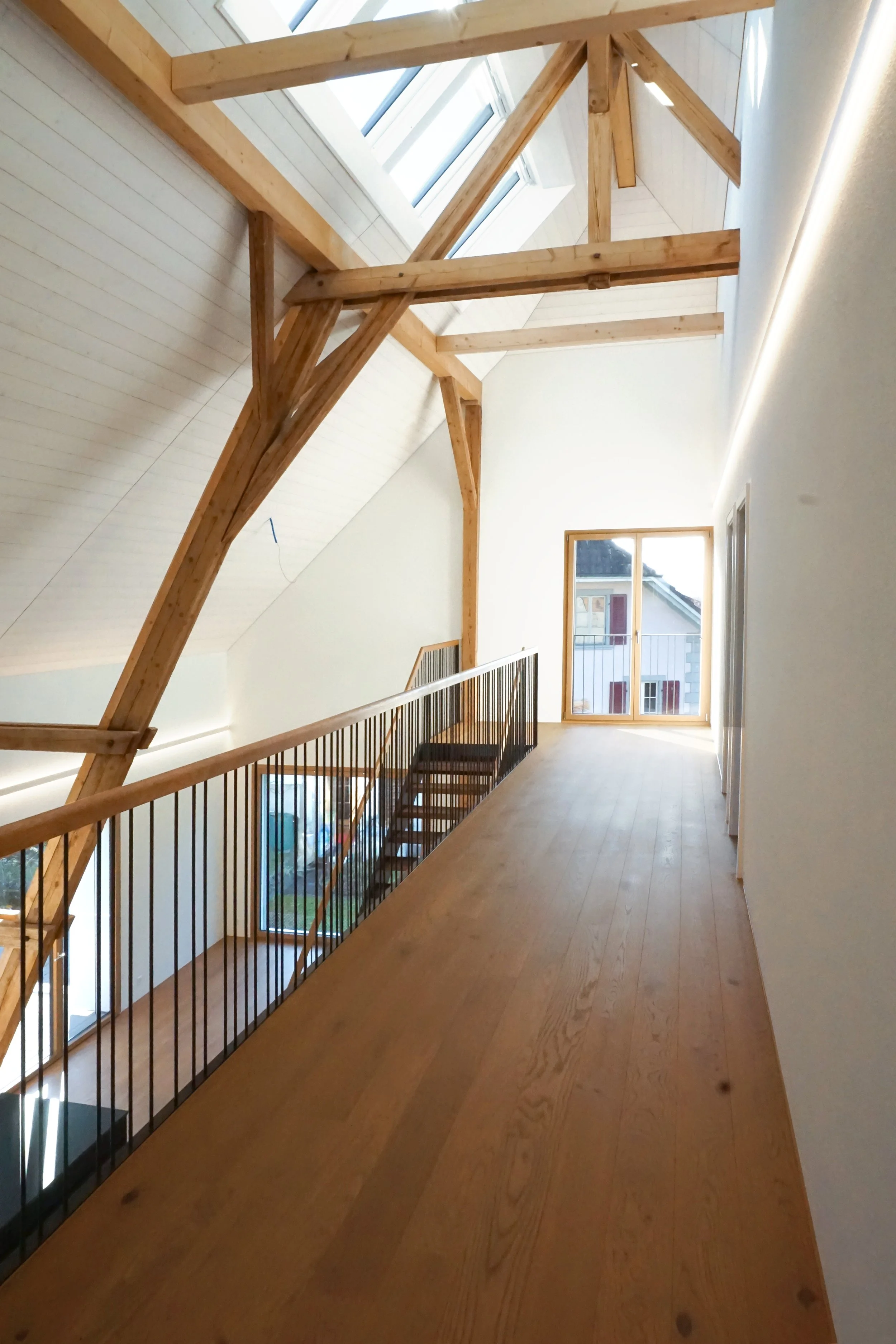 Langer Holzfußboden Heiliger Angelegenheit in einem hellen Raum mit großen Fenstern und Holzträgern.