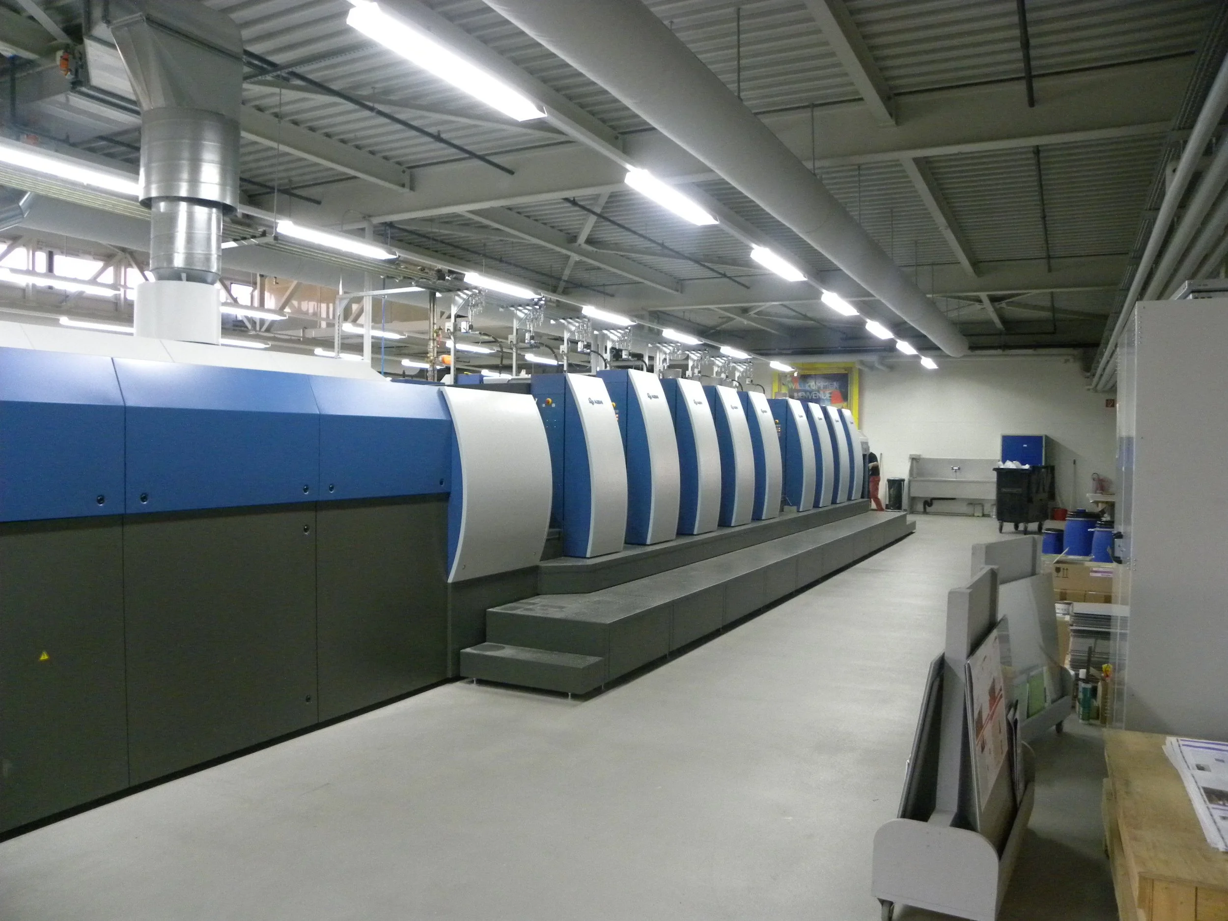 Eine große industrielle Druckmaschine in einem Fertigungsraum.