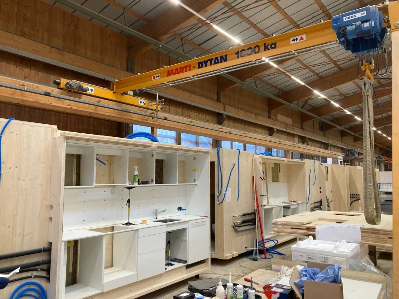 Innenaufnahme einer Werkstatt mit Holzrahmen, Werkzeugen und einer Deckenkranbahn.