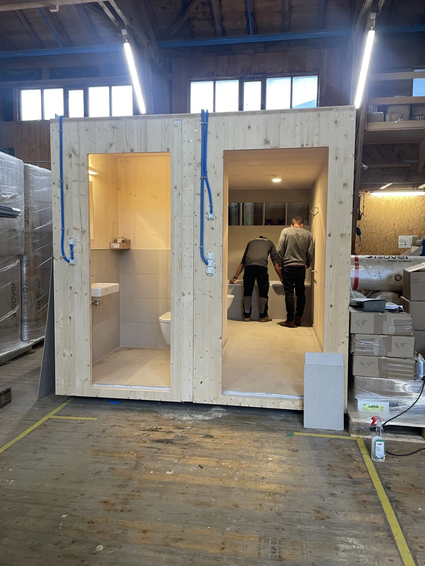 Bauteil mit einem Badezimmer und zwei Männern, die darin arbeiten, in einer Werkstatt