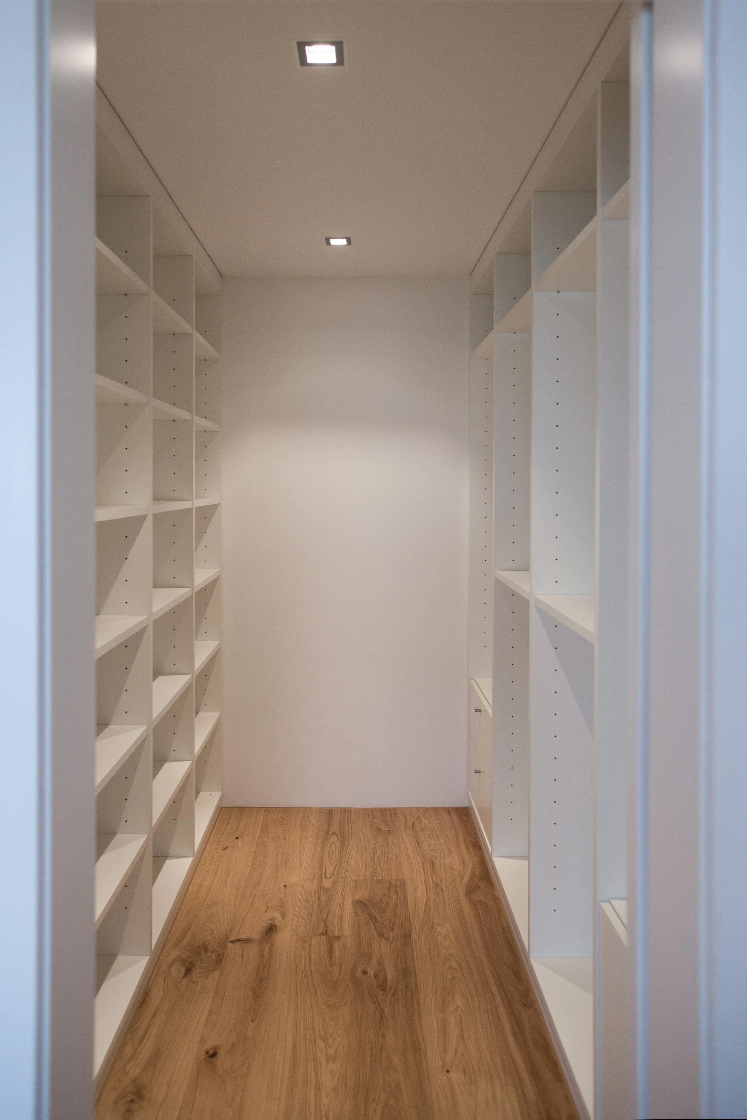 Leerer Flur mit weißen Regalen an beiden Seiten und Holzboden, Deckenbeleuchtung, textfrei und modern