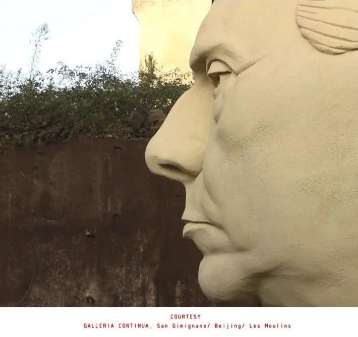 Close-up side view of a large stone sculpture of a human face, part of the Tiananmen Gate mural in Beijing, China.