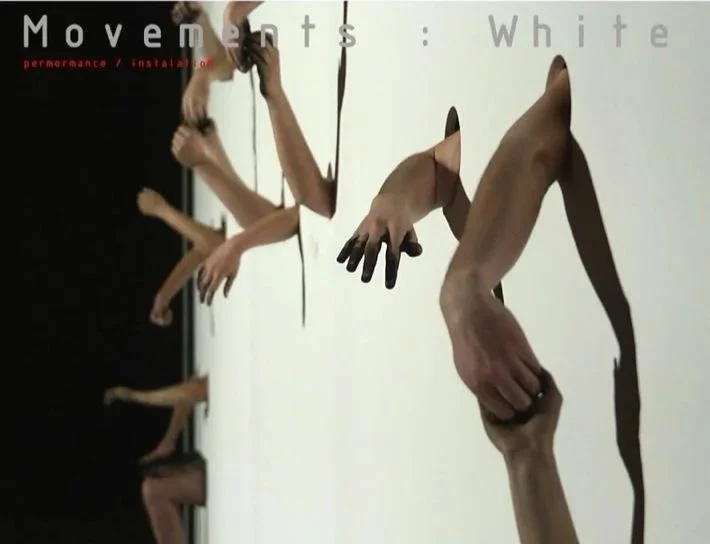 Art installation featuring arms and hands reaching through a mirror, creating a distorted reflection.