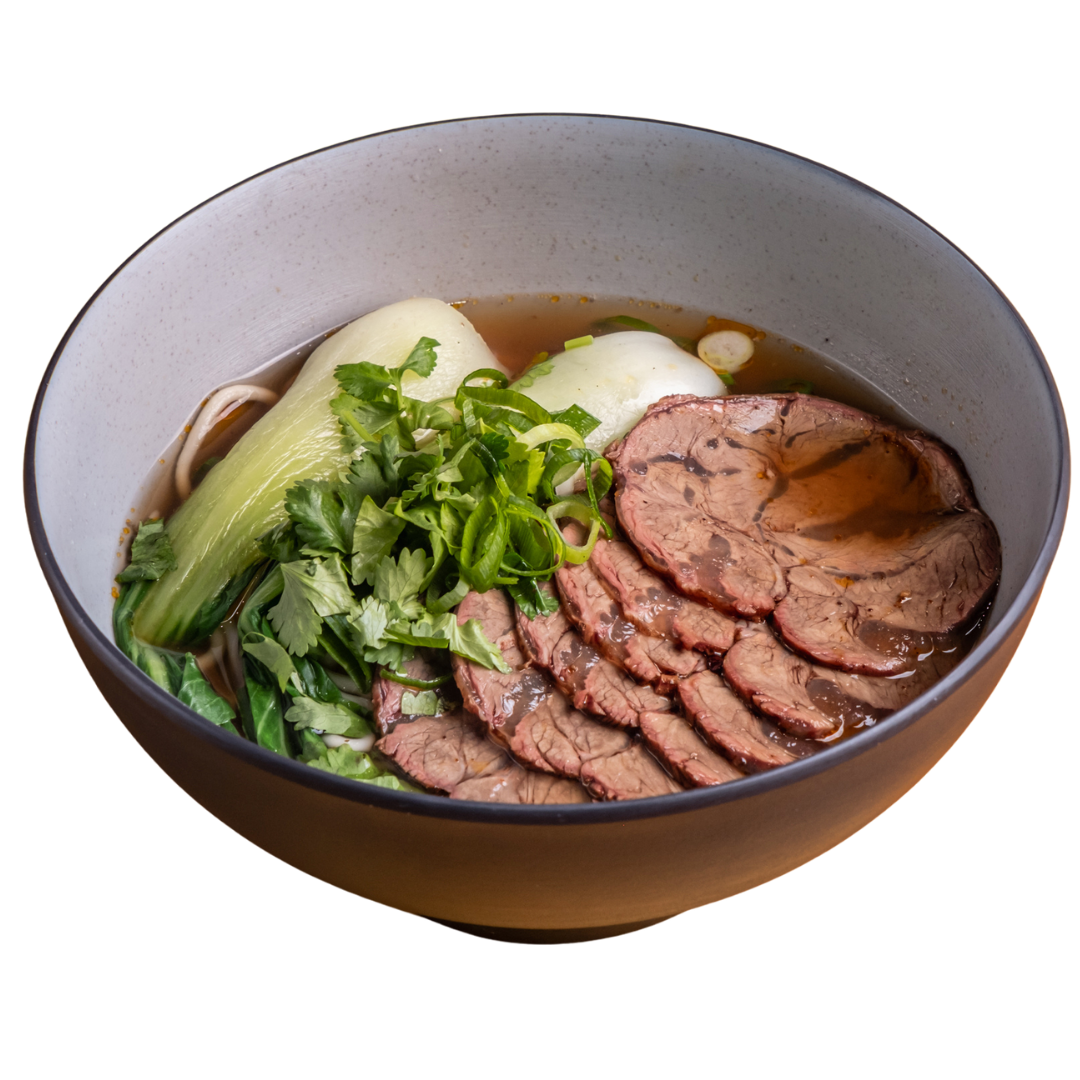 Bowl of Vietnamese pho with sliced beef, bok choy, green onions, cilantro, and a poached egg in broth.