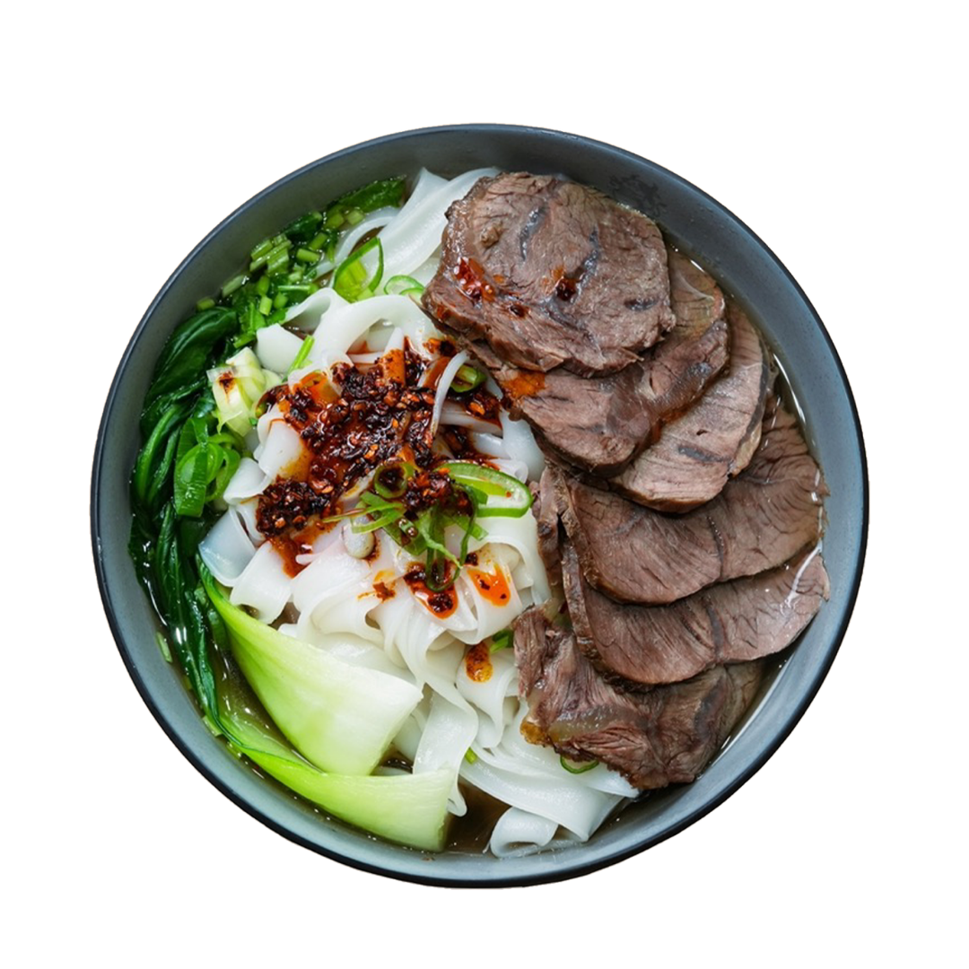 Bowl of beef stew with noodles, green vegetables, chopped green onions, and chili flakes.