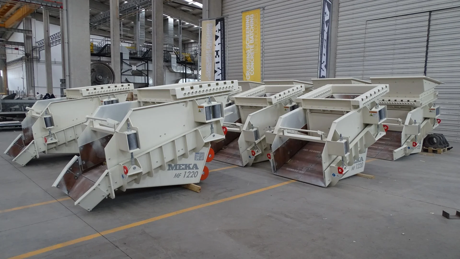 Multiple industrial vibratory feeders staged in a factory warehouse, ready for delivery.