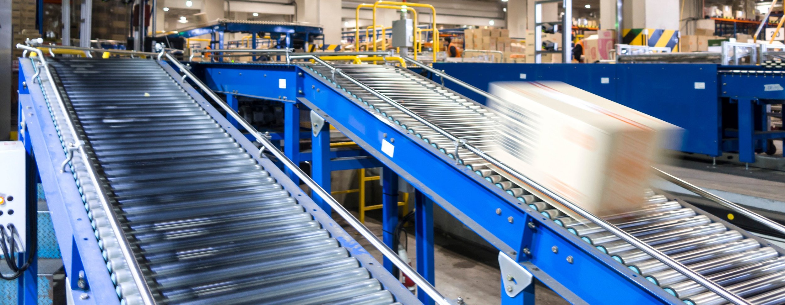 Blue conveyor belts in a warehouse moving boxes.
