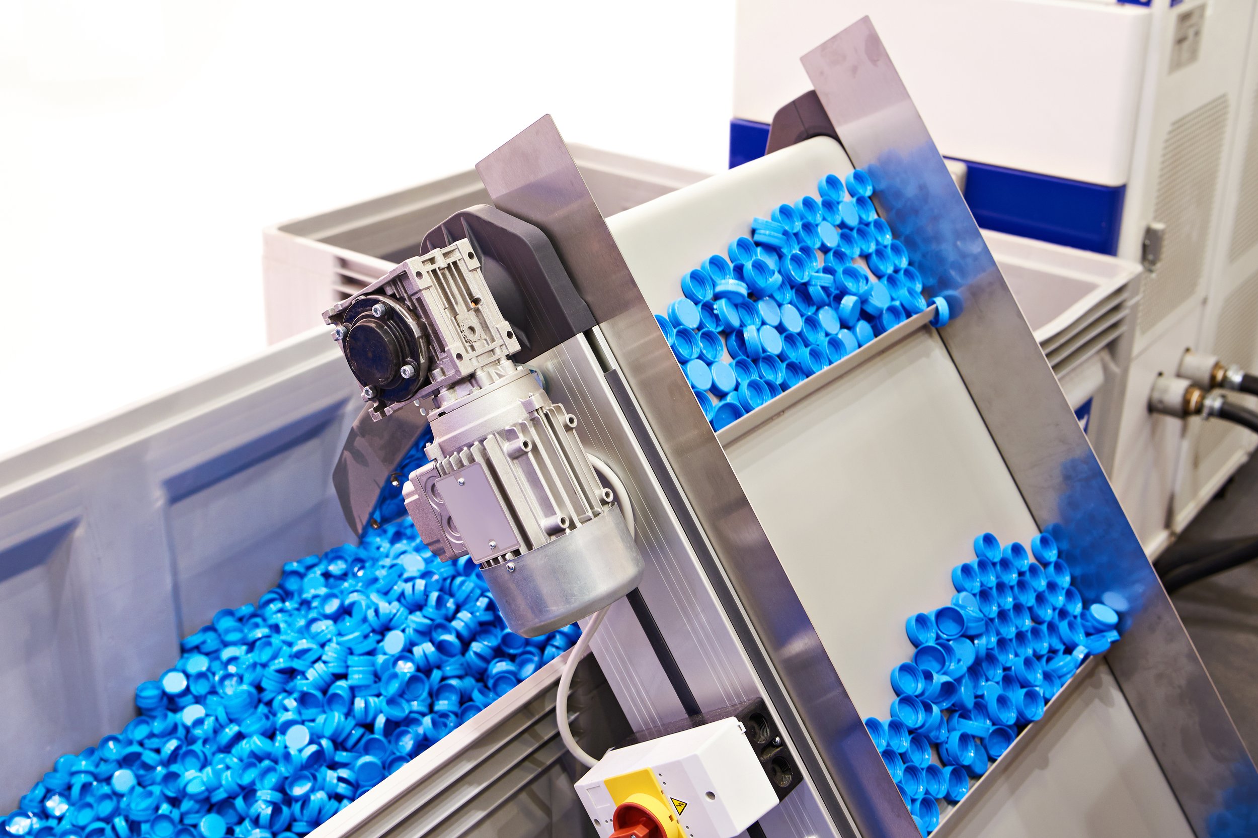 Automated machine filling blue plastic bottle caps in a manufacturing process.