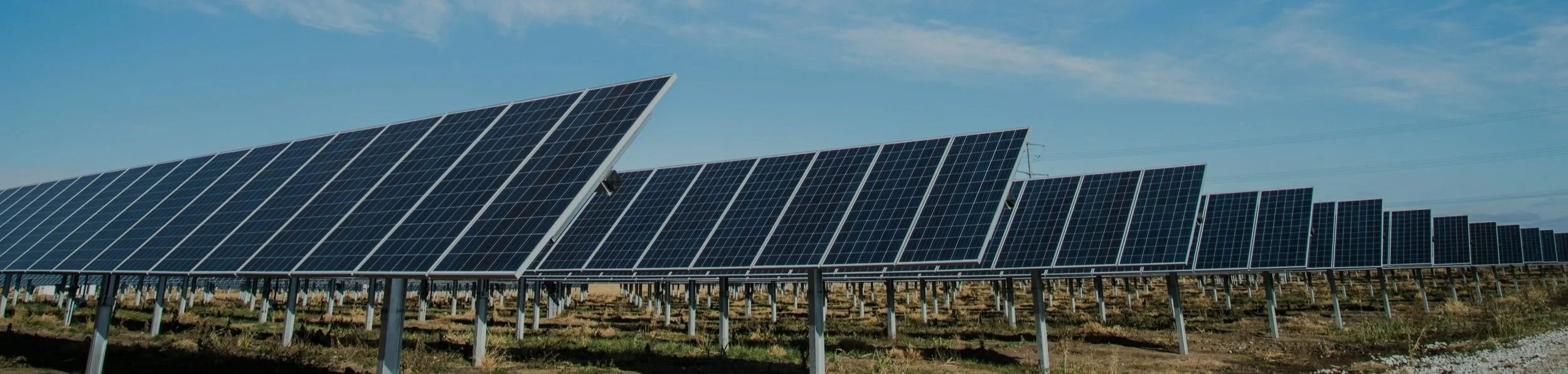 A large solar panel farm with multiple rows of solar panels under a clear blue sky.