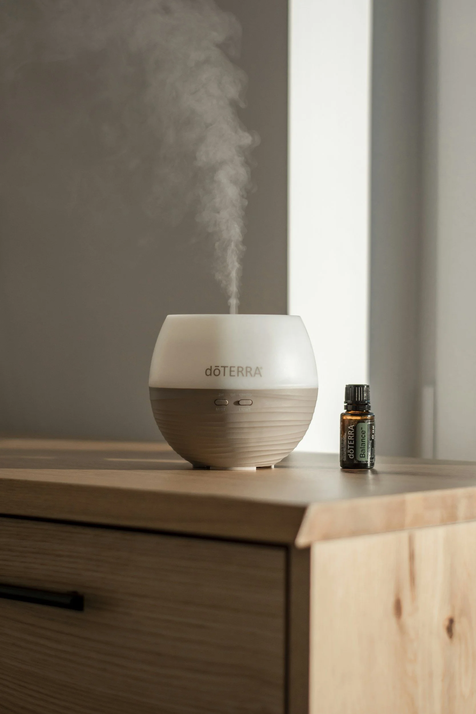 Essential oil diffuser with a bottle of essential oil on a wooden surface.